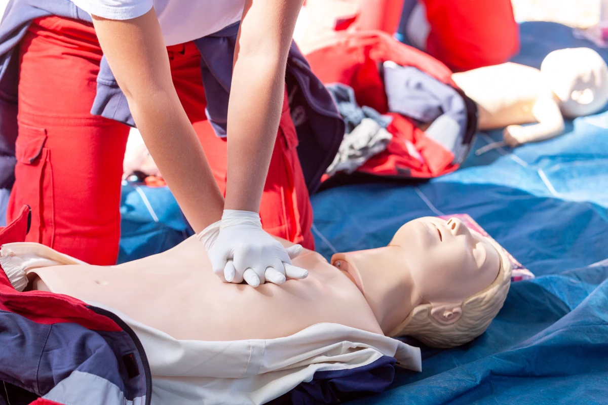 Students observing chest-compression practice on a training manikin.